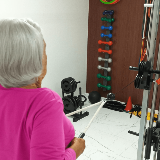 Uma paciente idosa usando um equipamento de musculação para melhorar sua mobilidade.